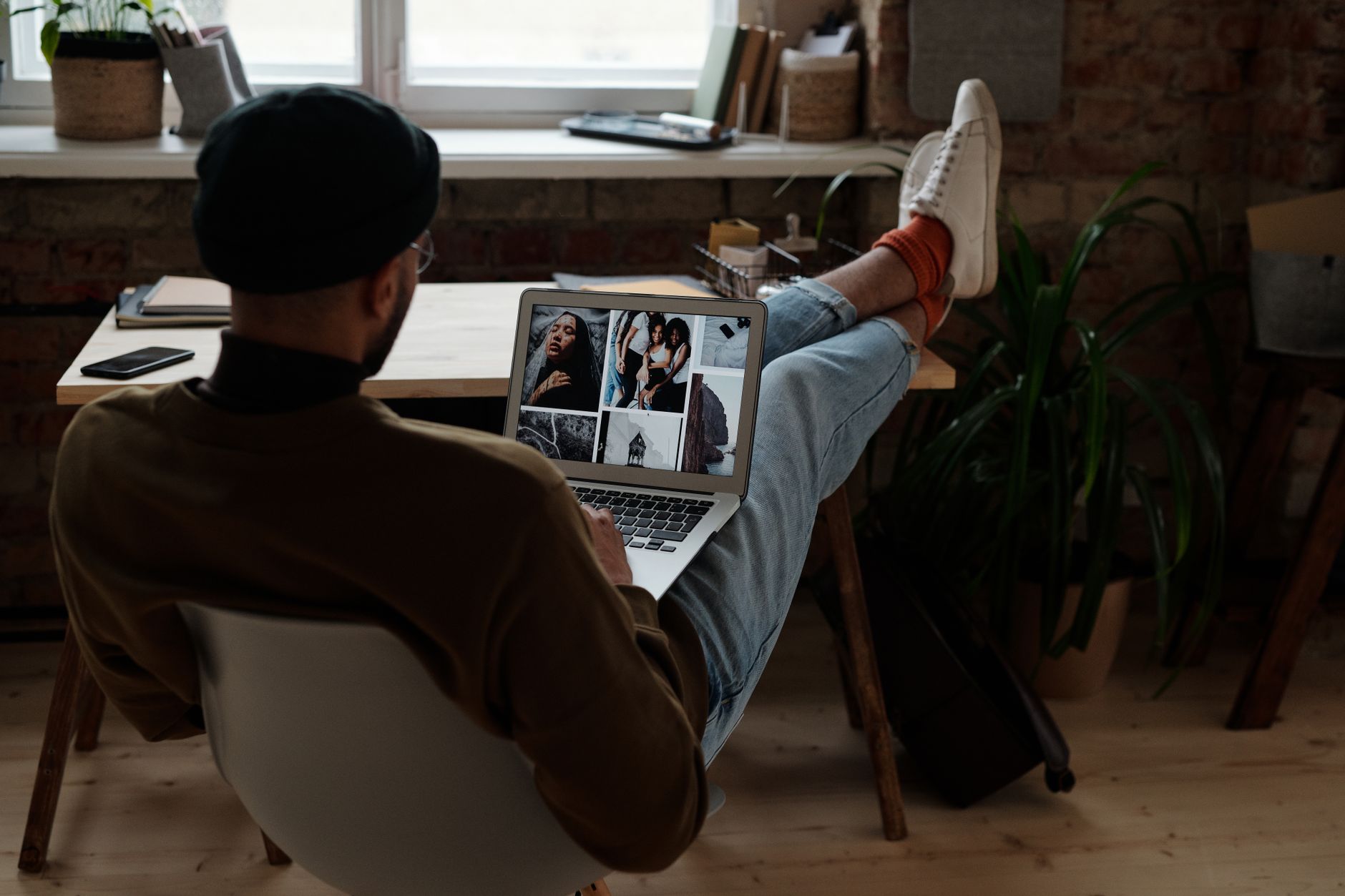 A focused tech blogger working at a dual-monitor desk setup with gadgets and screens around them in a modern home office
