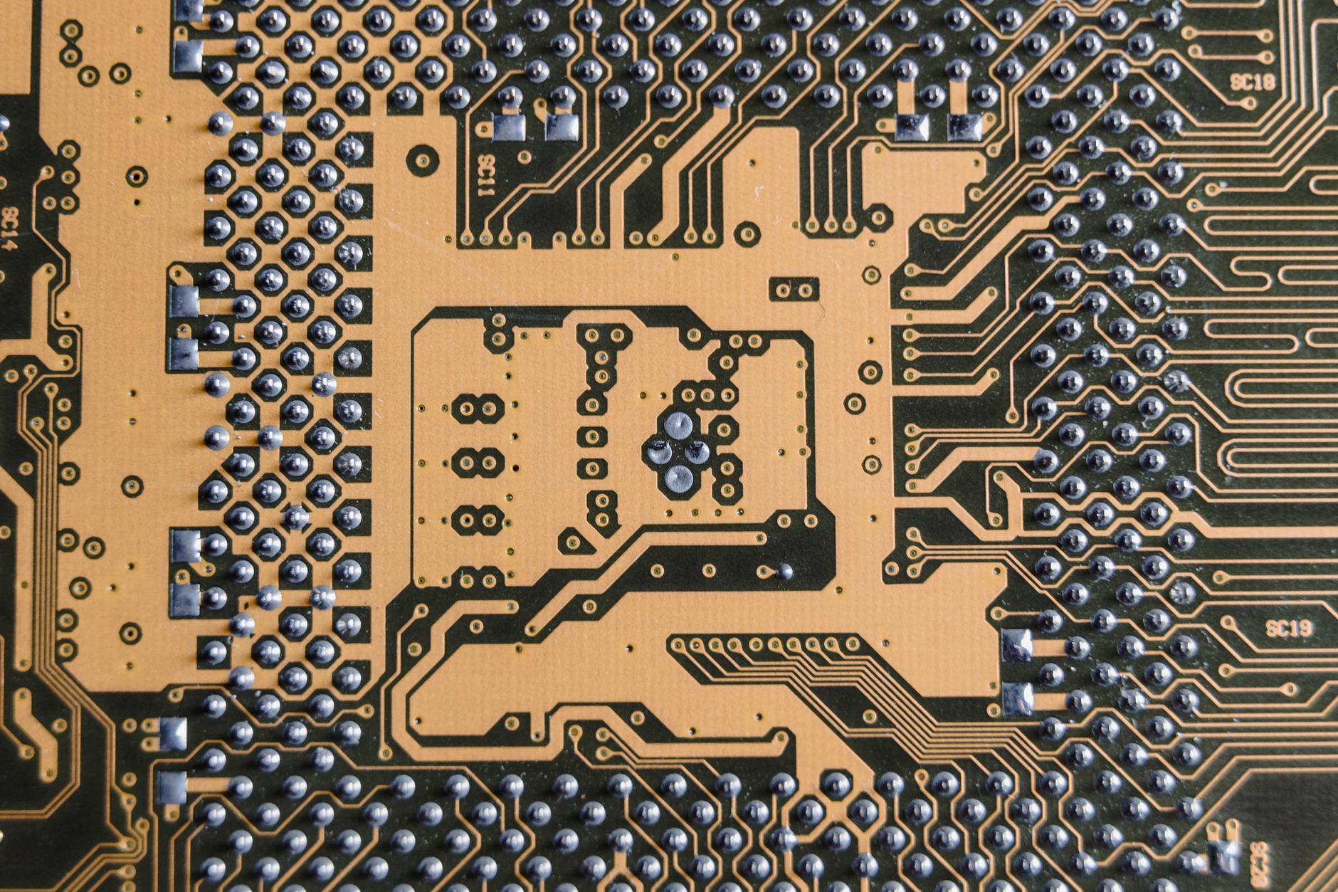 An extreme close-up of a glowing computer circuit board with detailed electronic components and blue-green LED lighting