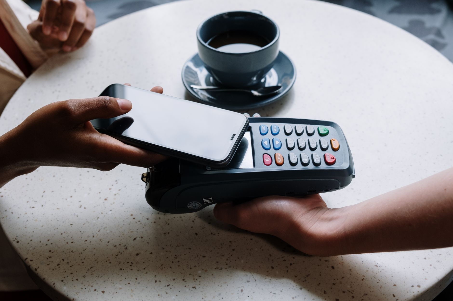 Person holding a smartphone to tap an NFC business card on a desk, illustrating contactless digital business card technology.