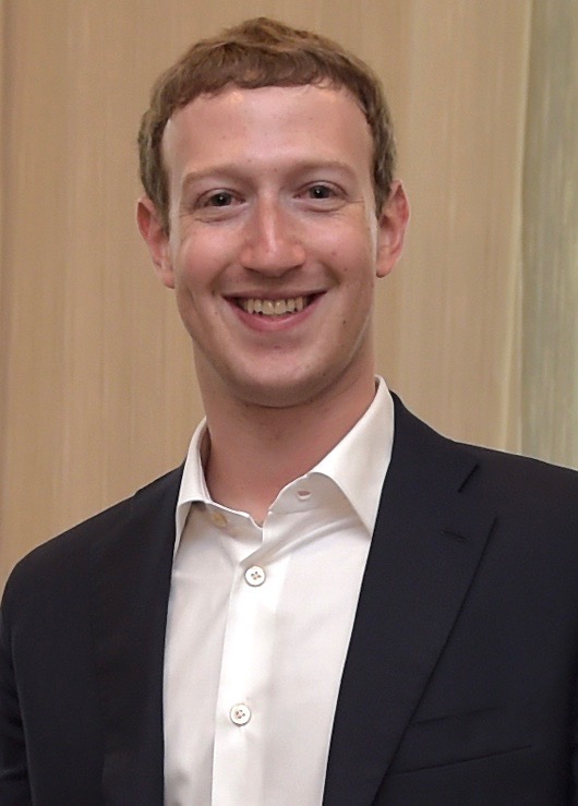 Photorealistic scene of Mark Zuckerberg on stage presenting virtual reality technology, with a large metaverse display behind him and a VR headset and controllers prominently shown.
