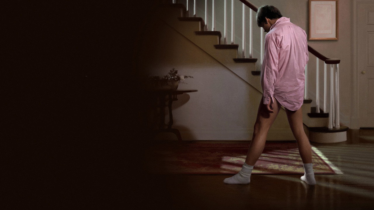 Teenager in white shirt, boxer briefs, and sunglasses sliding in socks on a hardwood floor, dancing in a retro 1980s-style living room