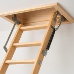 A close-up view of a retractable loft ladder mechanism attached to a ceiling.
